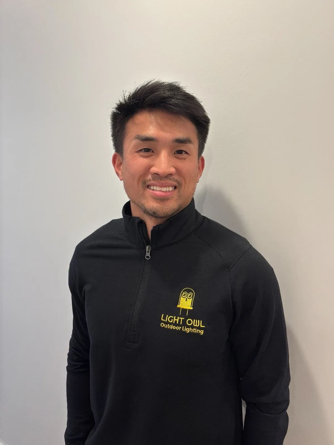 Man in black pullover with "Light Owl Outdoor Lighting" logo, smiling against a neutral background.