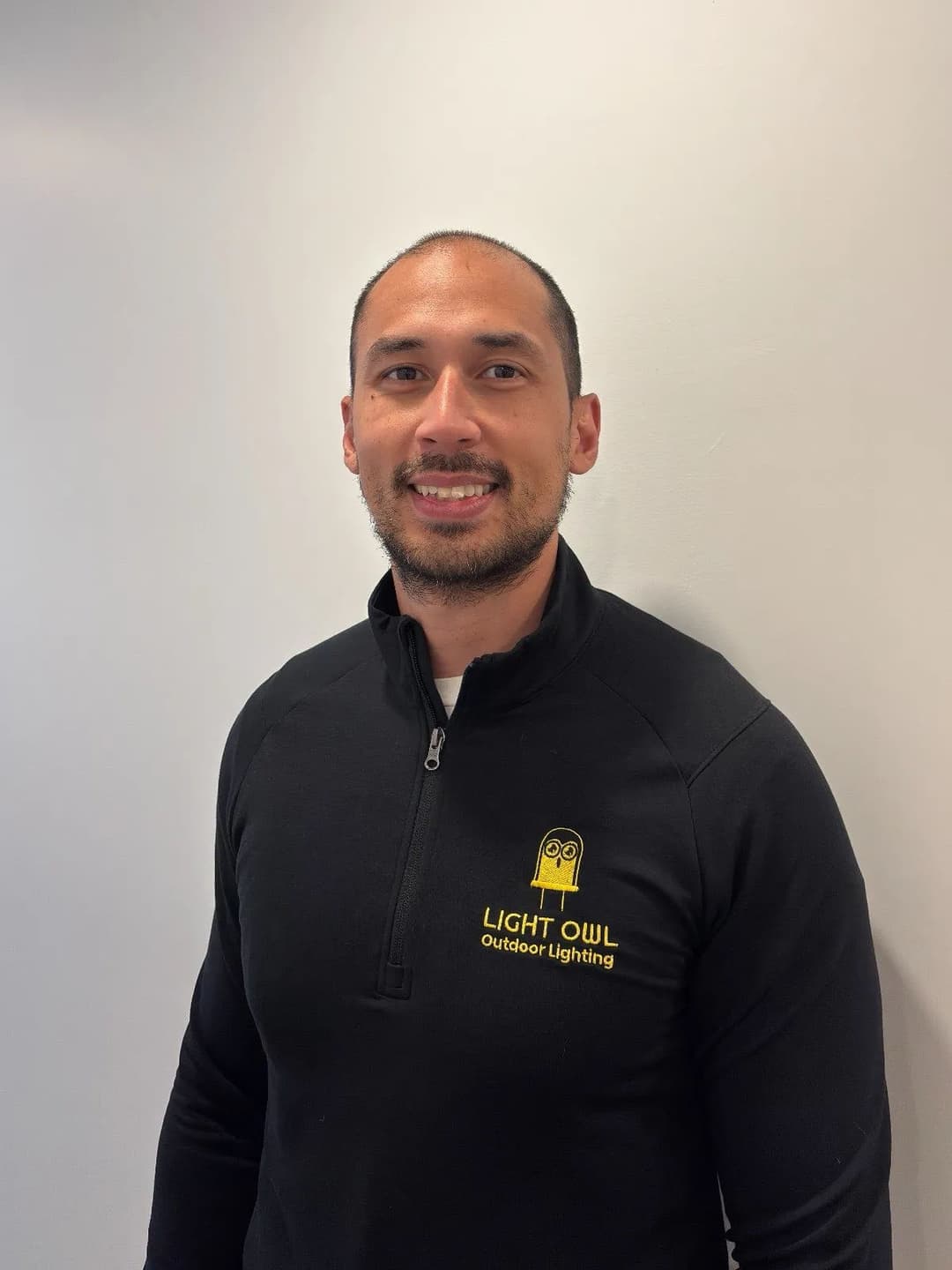 Man wearing a black sweater with "Light Owl Outdoor Lighting" logo on a light background.