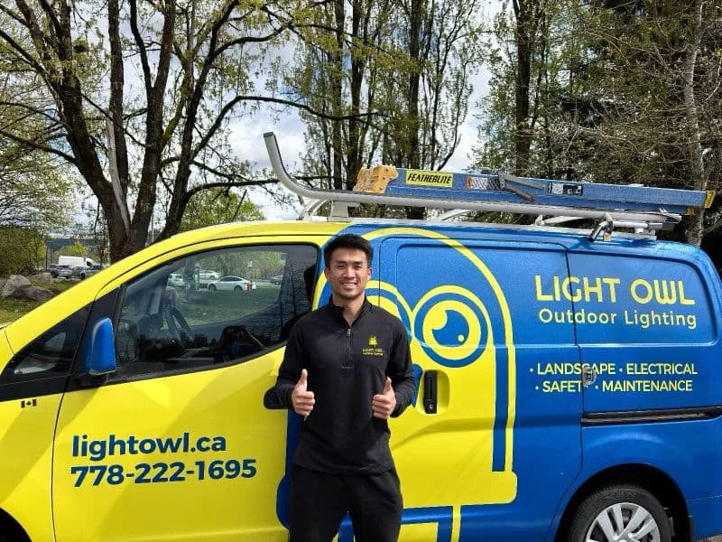 Light Owl employee giving thumbs up in front of branded van for outdoor lighting services.
