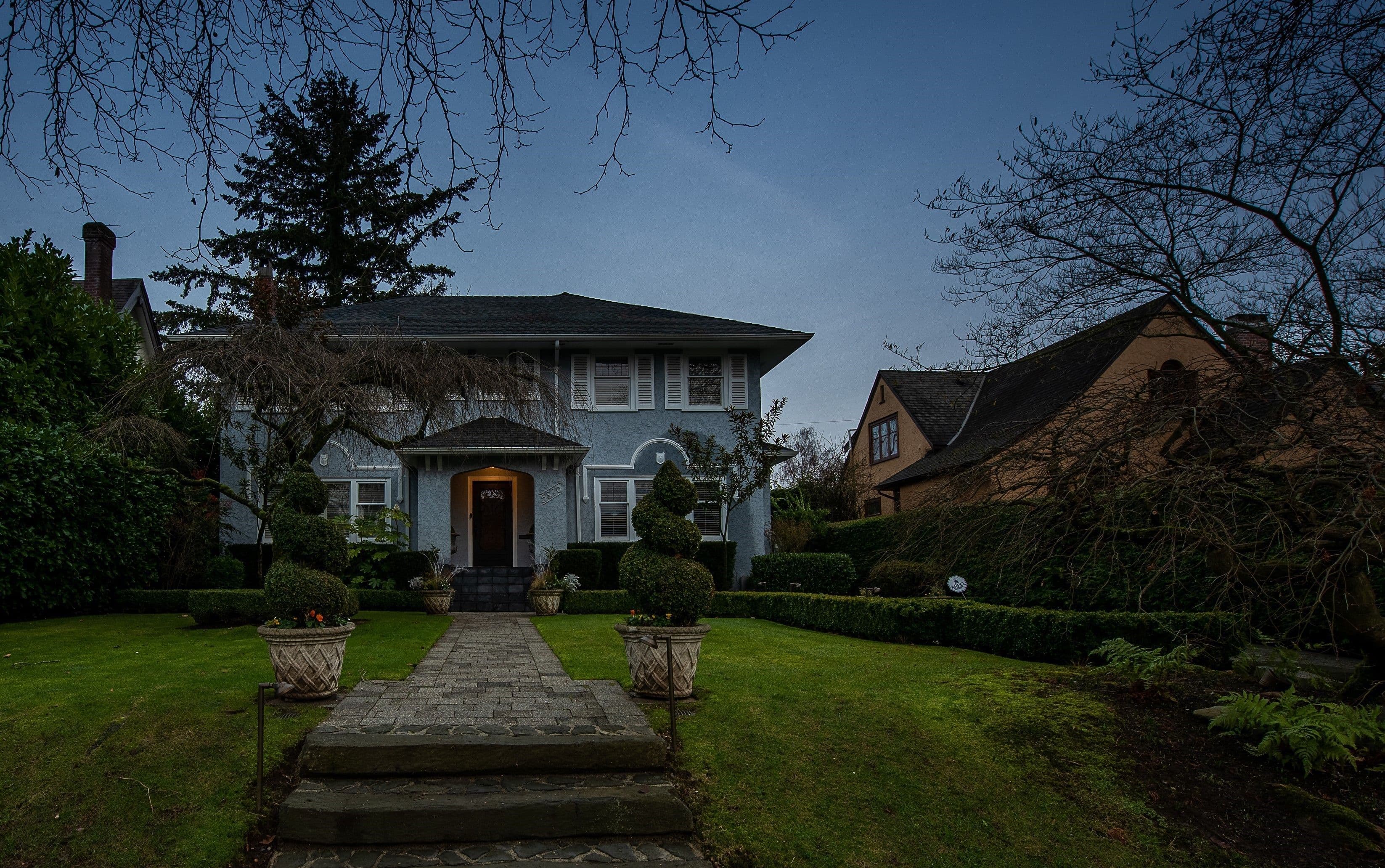 Elegant two-story house with landscaped front yard and pathway at dusk.