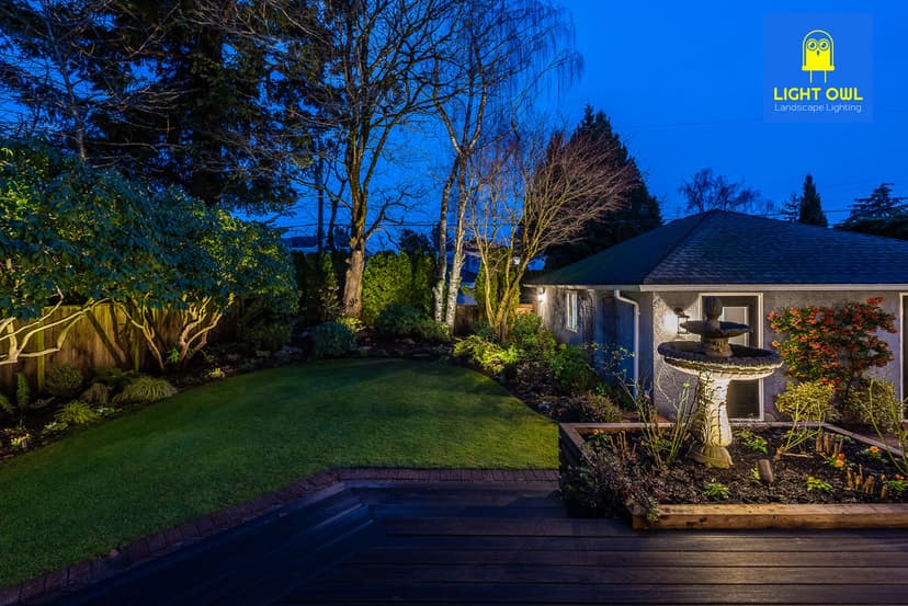 Illuminated garden at dusk with fountain and lush landscaping by Light Ouil Landscape Lighting.
